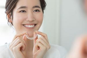 笑顔の女性がマウスピースを付けようとしている