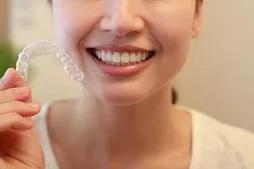 笑顔の女性がマウスピースを手に持っている